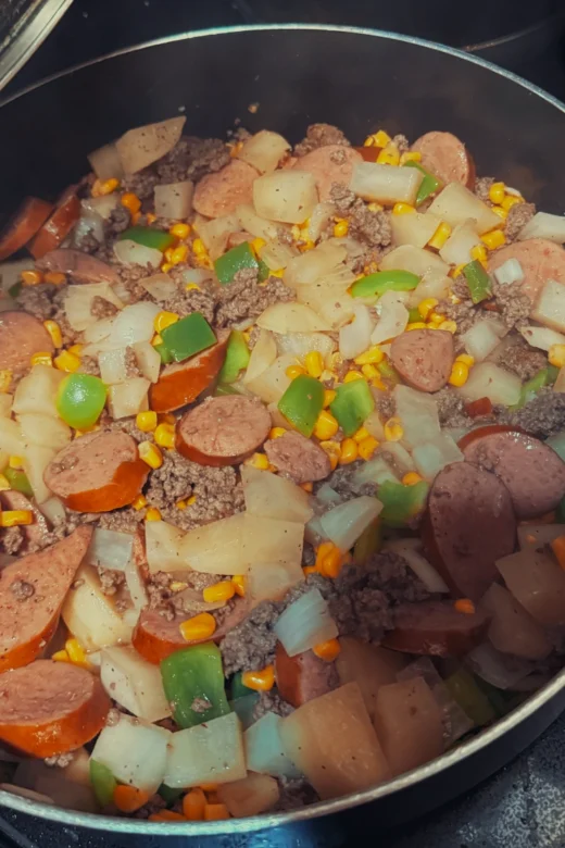 Firehouse stew cooking with ground beef, kielbasa, potatoes, corn, and green peppers.