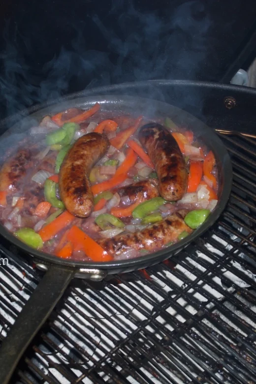 Italian sausages with peppers, onions and wine reduction on the grill.