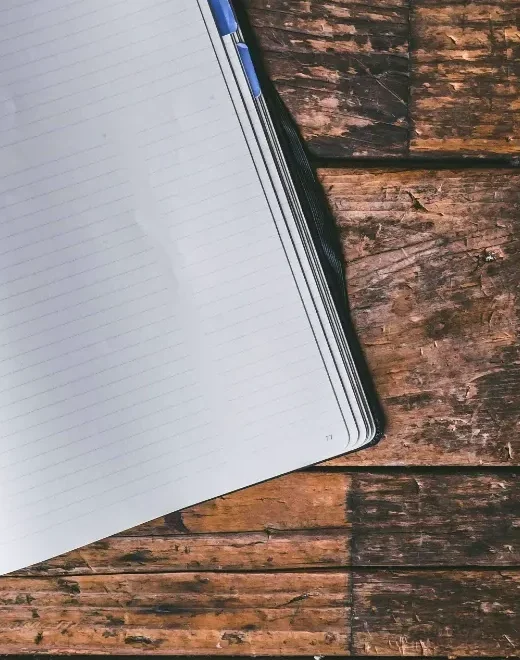 Open notebook and pen on a wooden desk.
