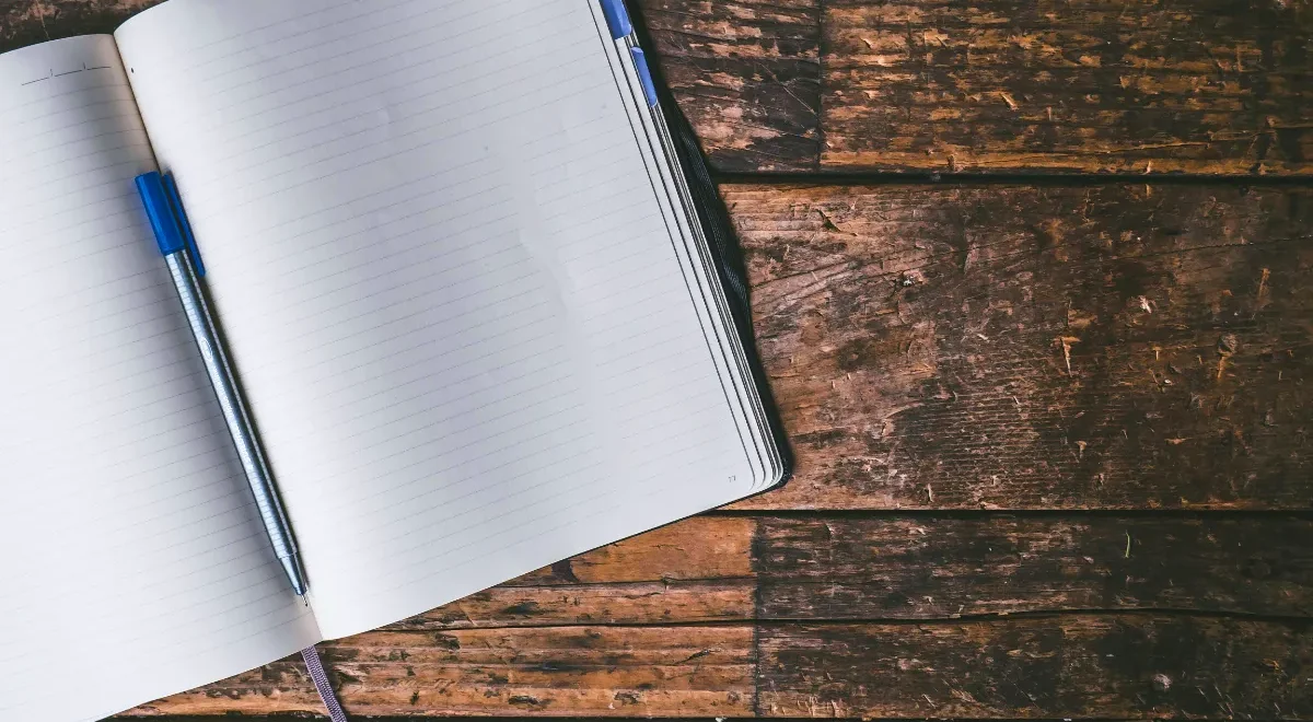 Open notebook and pen on a wooden desk.