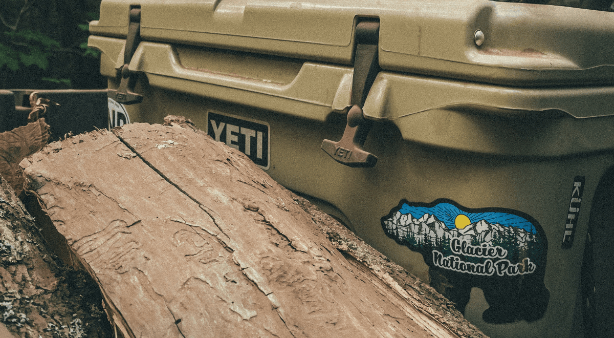 A yeti cooler in the woods behind a log.